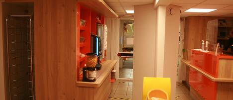 A restaurant interior with wooden accents, a counter with a coffee machine, and a yellow table with a box.