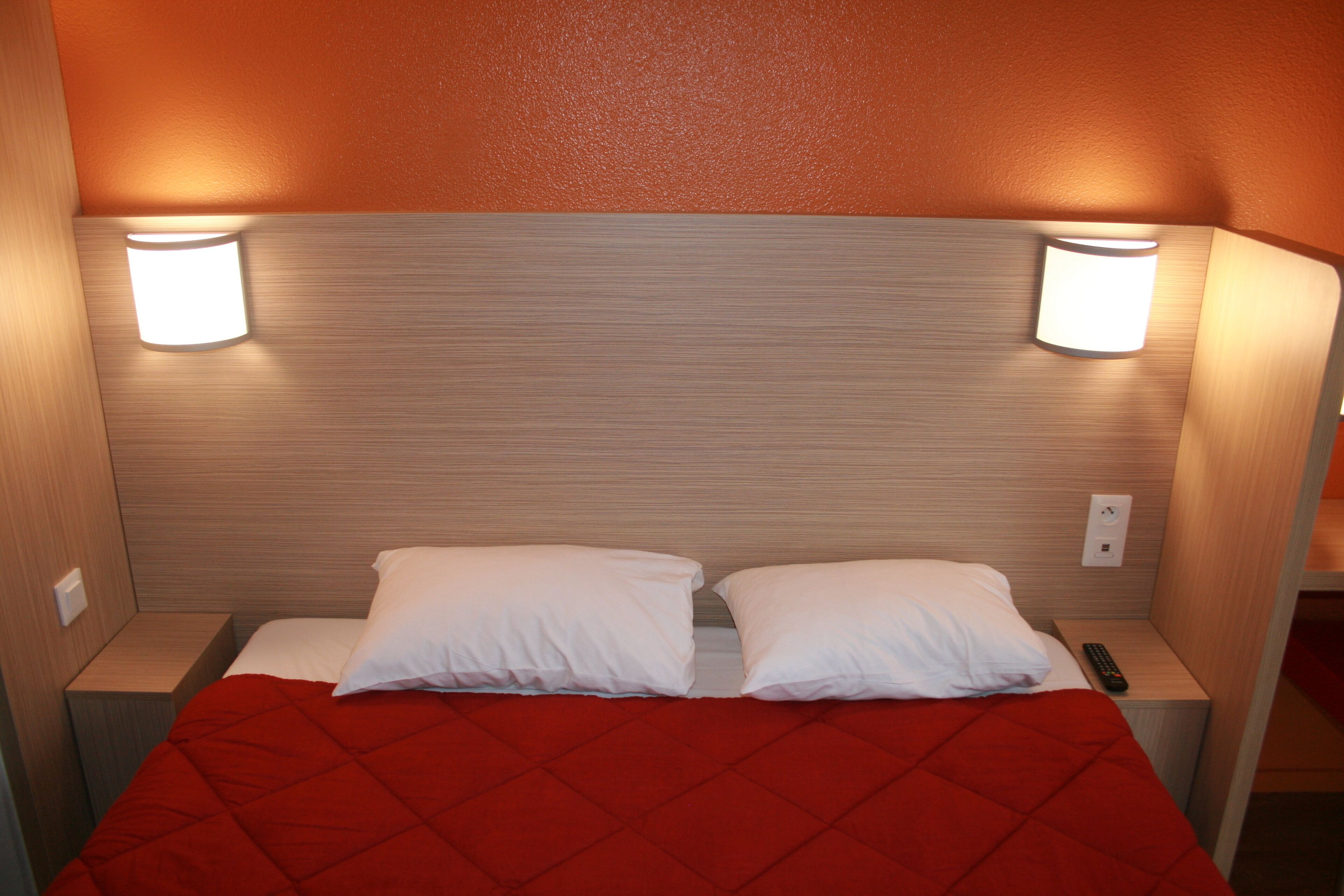 A hotel room with a bed, two bedside lamps, and a nightstand.