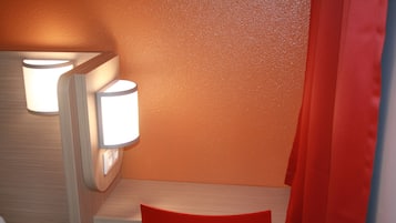 Une salle de bain avec un meuble-lavabo en bois, une chaise rouge et deux appliques murales.