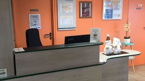A reception desk with a computer, a framed menu, and a small plant.