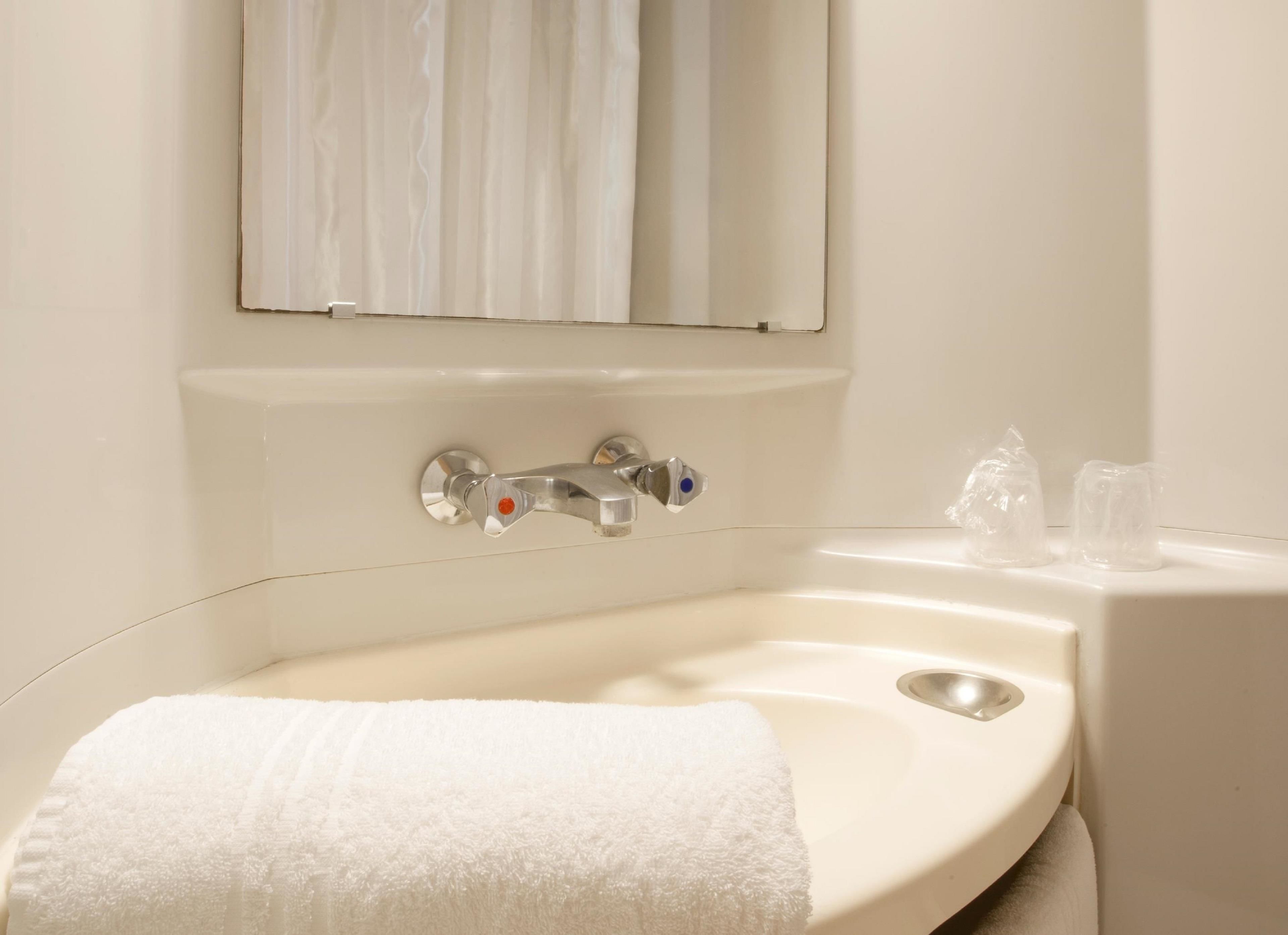 Une salle de bain avec un lavabo blanc, un miroir et une serviette.