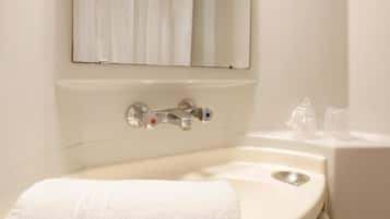 Un baño con lavamanos blanco, espejo y toalla.