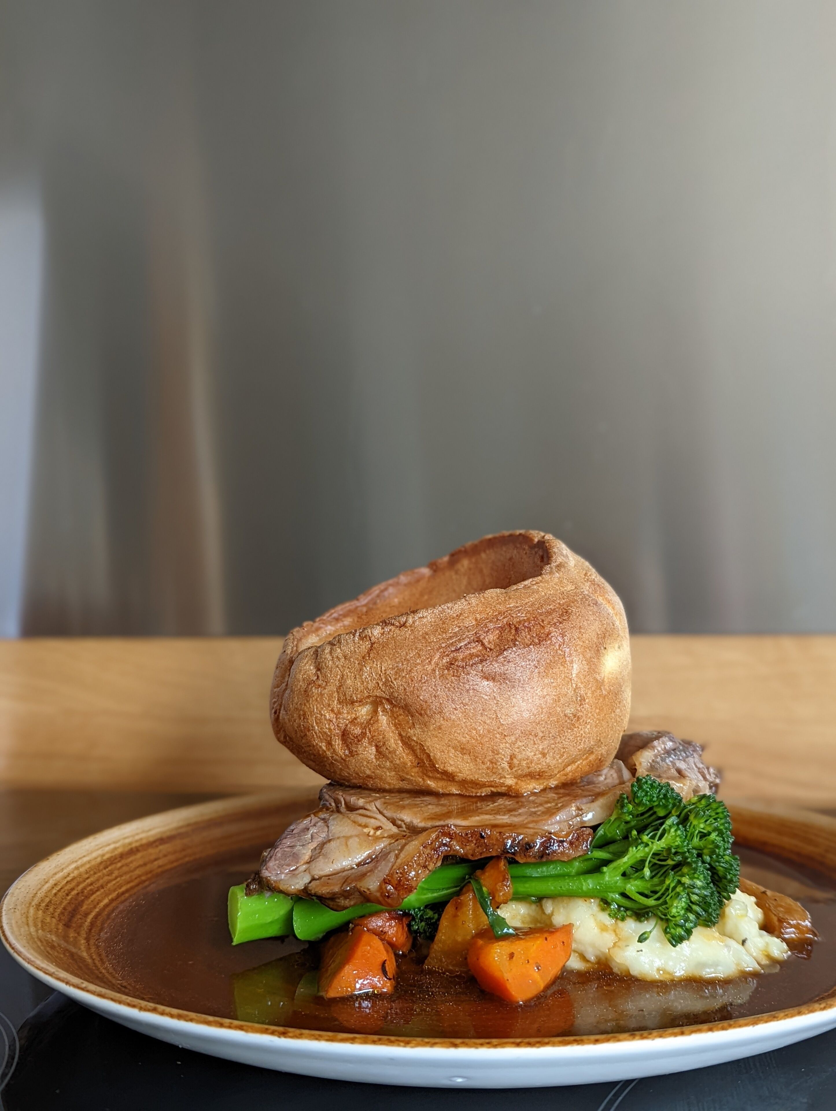 A plate of roast beef with vegetables and Yorkshire pudding.