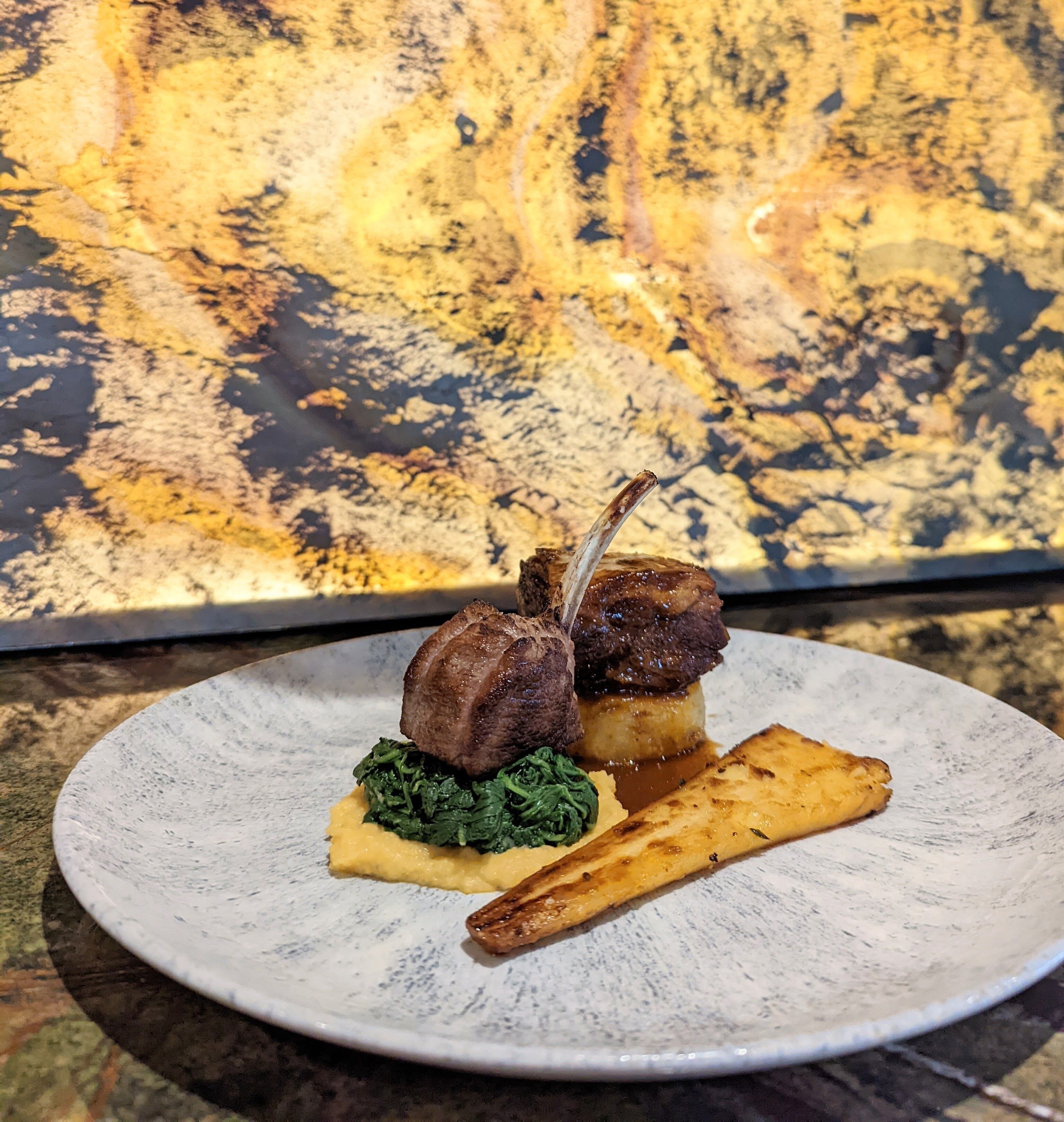 Une assiette contenant un morceau de viande, des légumes verts et une pomme de terre.