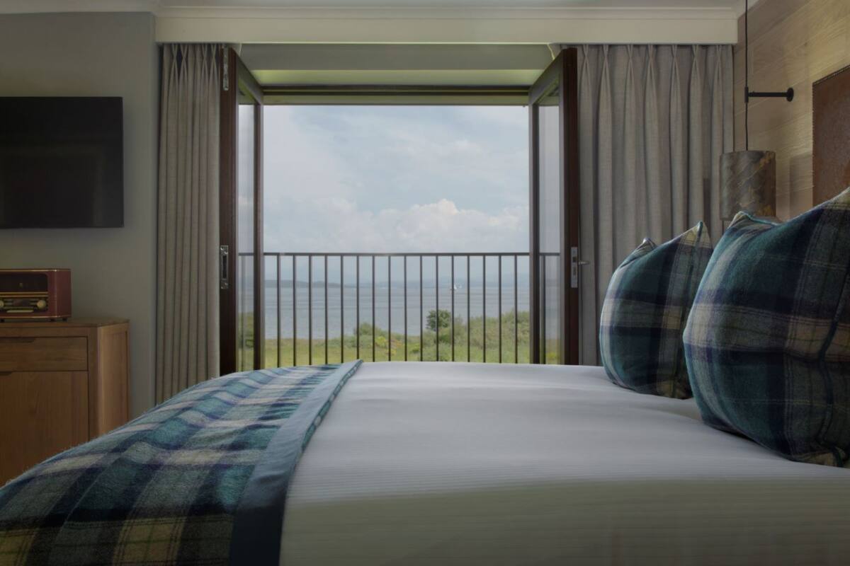A bedroom with a bed, a television, and a view of the outdoors.