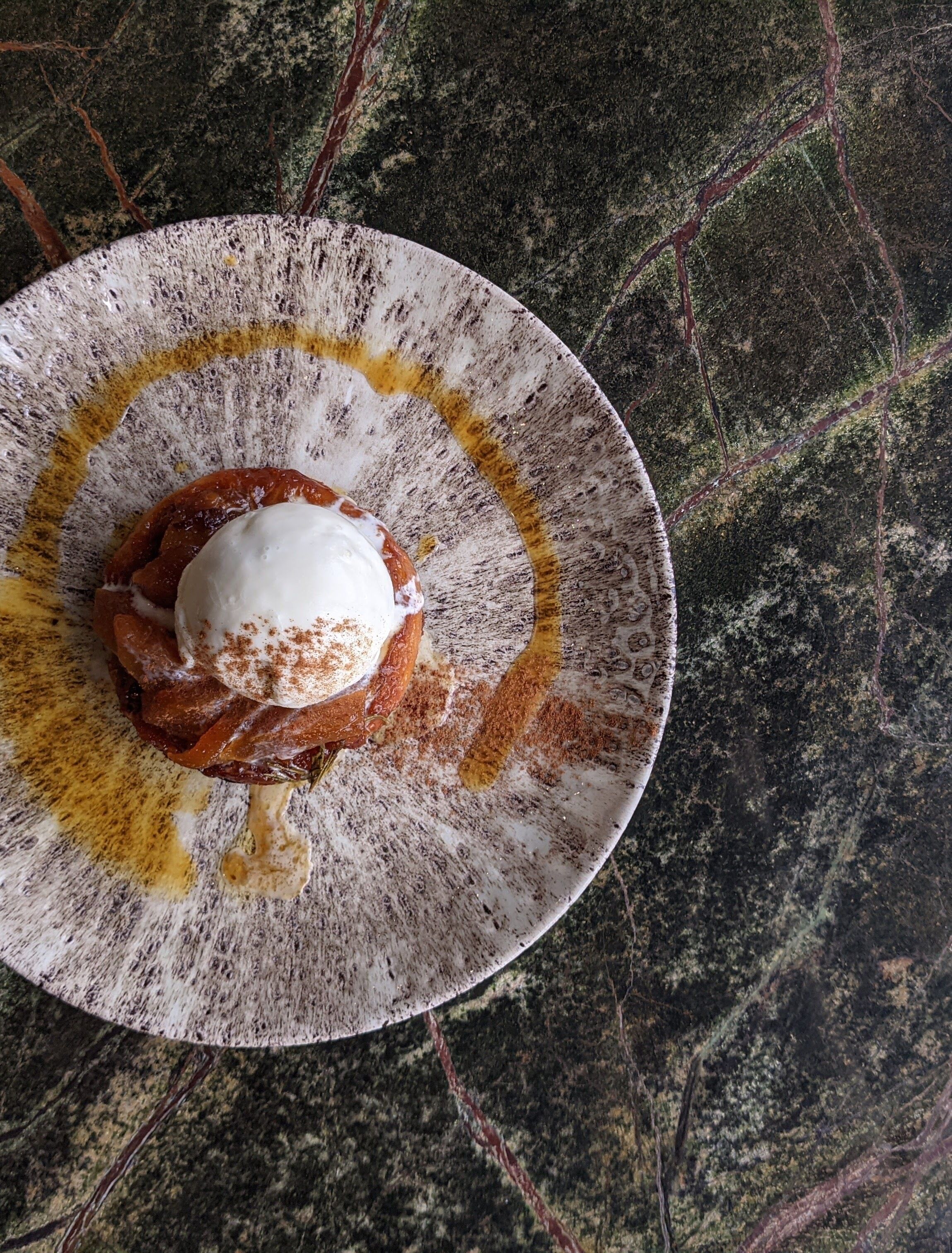 A dessert on a plate with a rustic design, placed on a textured surface.