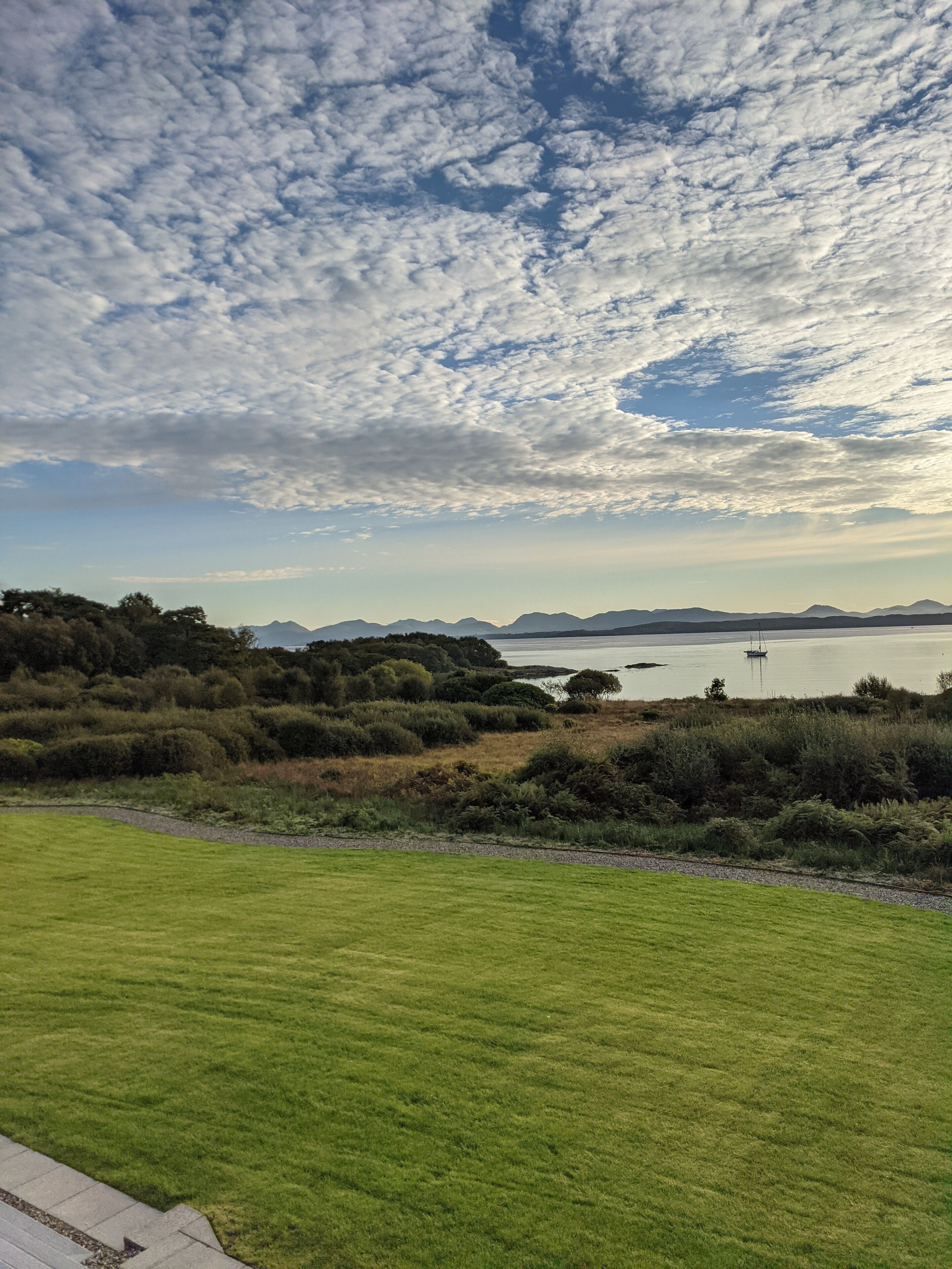 A grassy field with a body of water and distant mountains.