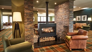 A cozy room with a fireplace, a sofa, a lamp, and a dining area in the background. - The Isle of Mull Hotel and Spa (Isle of Mull)