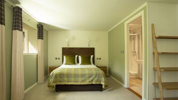 A bedroom with a bed, a nightstand, a wooden ladder, and a bathroom visible through an open door.