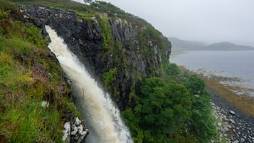 A waterfall cascading down a rocky cliff into a body of water.