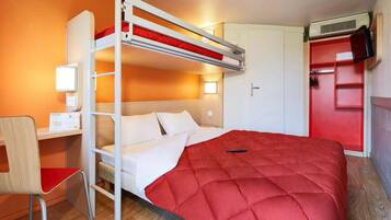 A bunk bed with a red quilt, a desk with a lamp, and a wardrobe with a red door.
