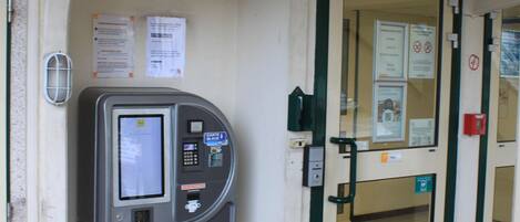 Des toilettes publiques équipées d’un distributeur automatique, d’une pancarte indiquant « PREMIÈRE CLASSE » et d’une porte à panneaux de verre.