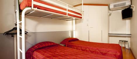 A bunk bed room with a red bedspread, a white air conditioning unit, and a small stool.