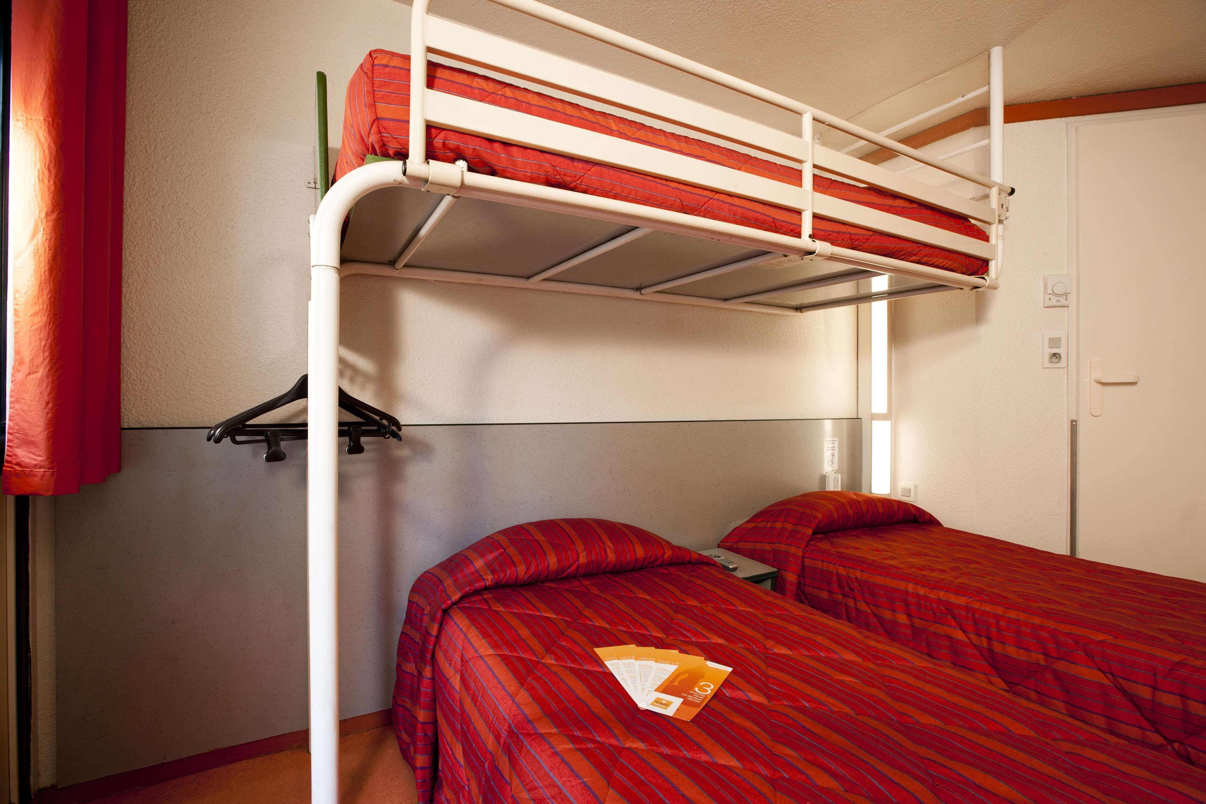 Habitación con literas, un armario y una pequeña mesa con un libro.
