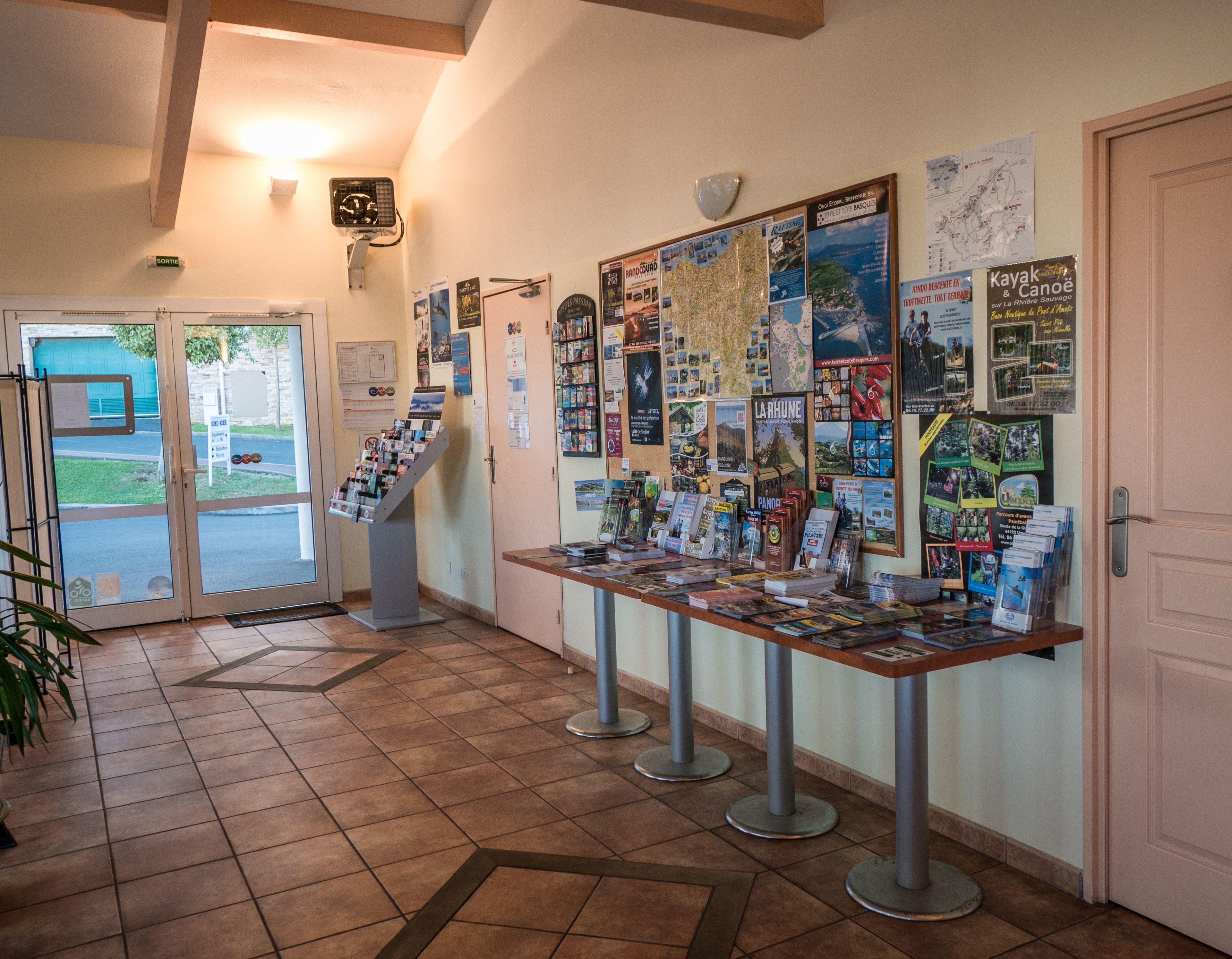 A hallway with a display of travel brochures and maps on the wall.
