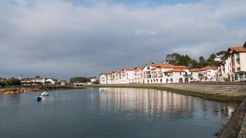 Una vista sul lungofiume con edifici lungo il fiume, una barca ormeggiata vicino alla riva e un faro sullo sfondo.