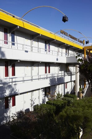 A multi-story hotel with a yellow and white facade, multiple balconies, and a staircase leading to the upper floors. - Premiere Classe Beziers (Villeneuve-les-Beziers)