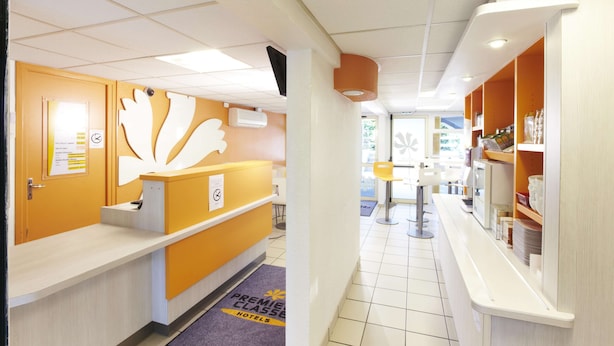 A hotel reception area with a reception desk, a bulletin board, and a counter with a menu. - Premiere Classe Beziers (Villeneuve-les-Beziers)