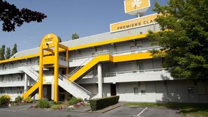 Un hotel con un llamativo esquema de color amarillo y blanco, con un cartel que dice "HOTEL PREMIERE CLASSE" y una escalera que conduce a la entrada.