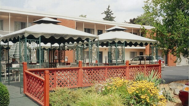 A courtyard with outdoor seating, a red fence, and yellow flowers. - Meadow Court Inn (Ithaca)