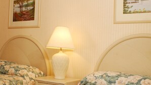 A bedroom with two beds, each with floral bedding, a bedside table with a lamp, and framed pictures on the wall. - Meadow Court Inn (Ithaca)