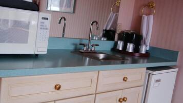 A kitchenette with a microwave, sink, and coffee maker.