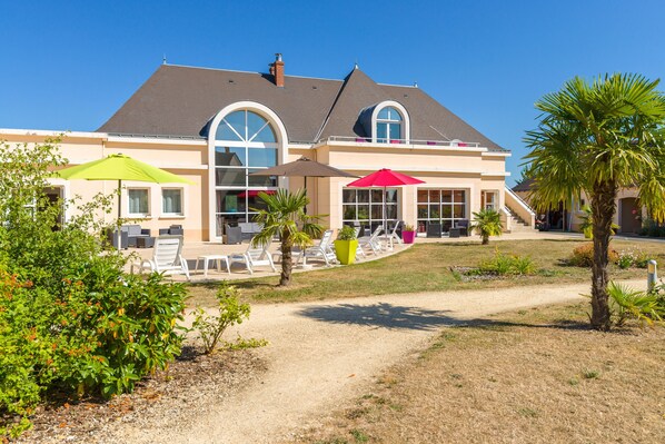 A two-story house with a patio area featuring outdoor seating and umbrellas. - Résidence Lagrange Vacances Les Jardins Renaissance (Azay-le-Rideau)