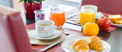 A breakfast setting with croissants, orange juice, and a cup of coffee on a table.