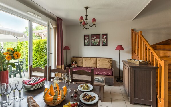 Un comedor con una mesa lista para dos personas, un sofá y una escalera.