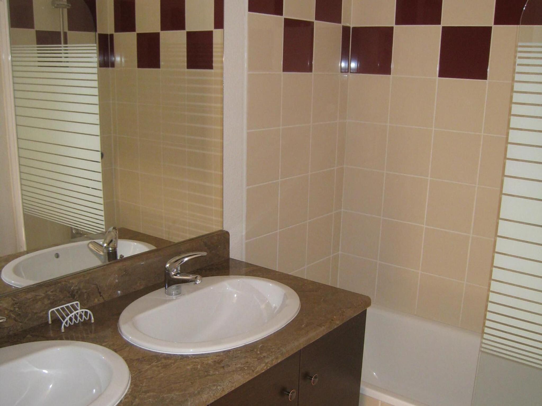 Un baño con dos lavamanos, un espejo y una bañera.
