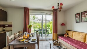 Uma sala de jantar com mesa posta para quatro pessoas, um sofá e uma janela com cortinas.