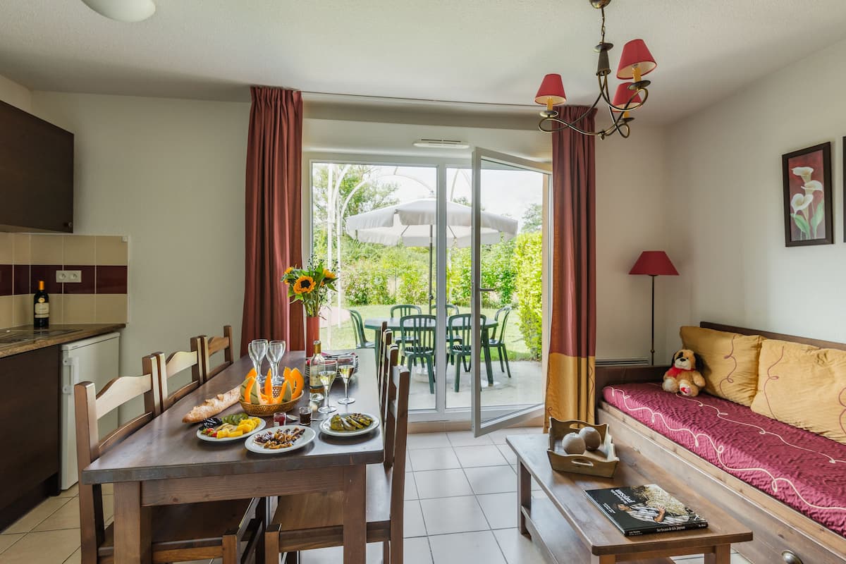 A dining area with a table set for four, a sofa, and a window with curtains.