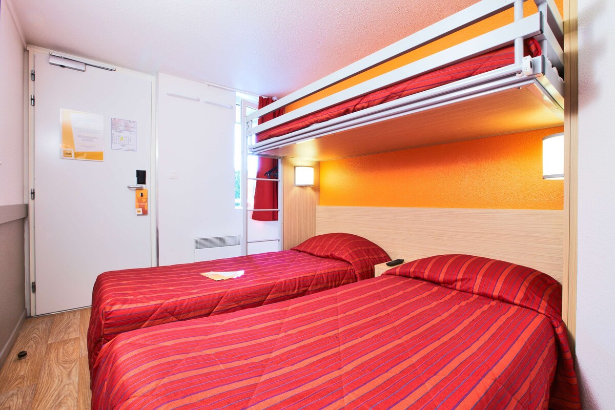 A room with two beds, a bunk bed above, and a white wardrobe.