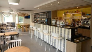 A modern bar area with a counter, stools, and a television screen. - Premiere Classe SETE - Balaruc (Balaruc-le-Vieux)