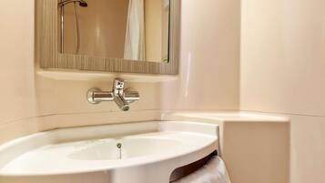 Une salle de bain avec un lavabo blanc, un miroir et une douche.
