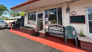 A building with a 'OFFICE' sign, a bench, a clock, and a 'NOTICE' sign on the door.