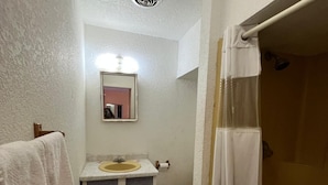 A narrow bathroom with a toilet, sink, and shower.