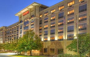 Un hôtel Sheraton avec de nombreux étages, de grandes fenêtres et des drapeaux américains.