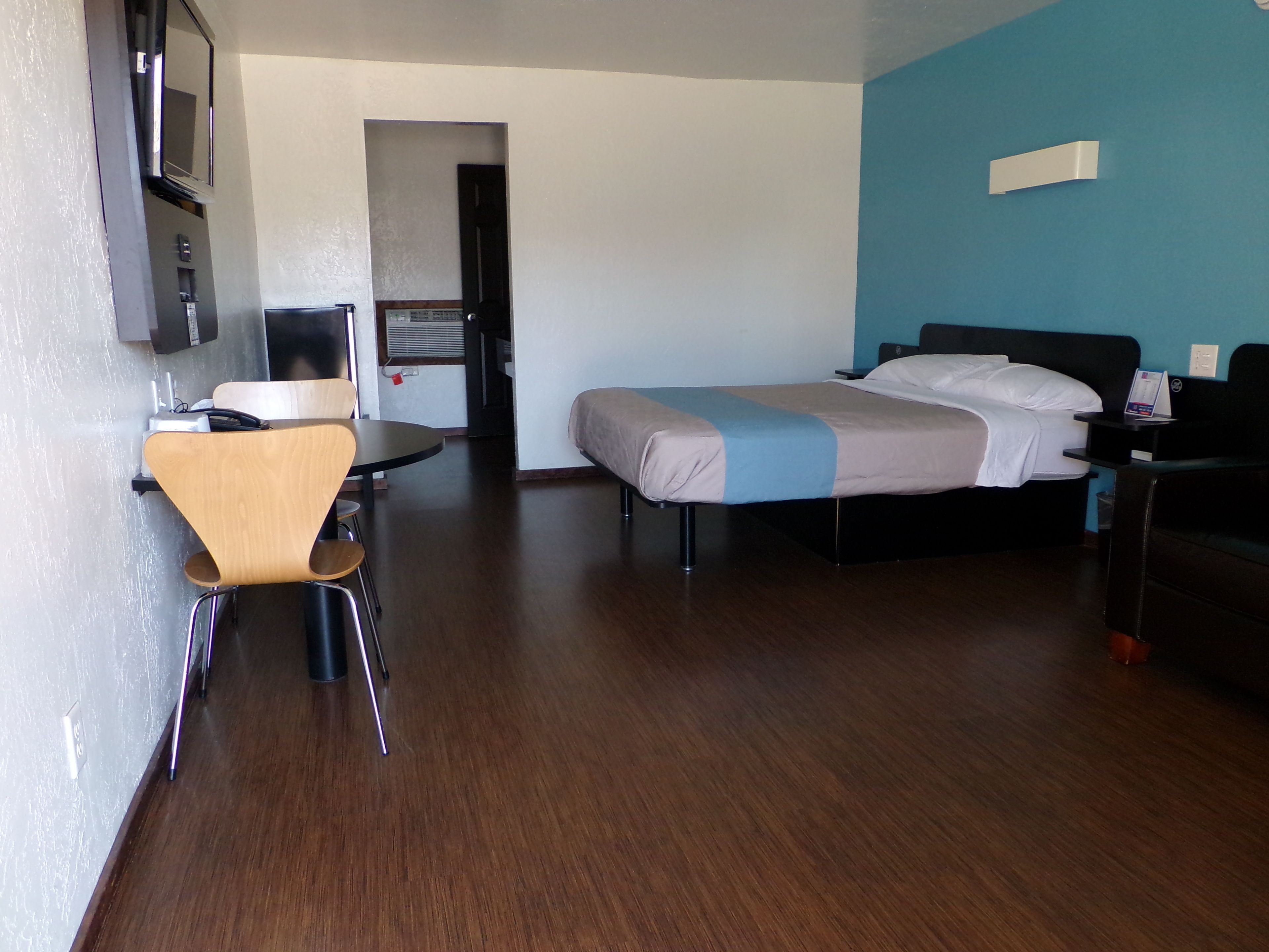 Habitación de hotel con cama, escritorio, silla, televisor y puerta que da a un baño.