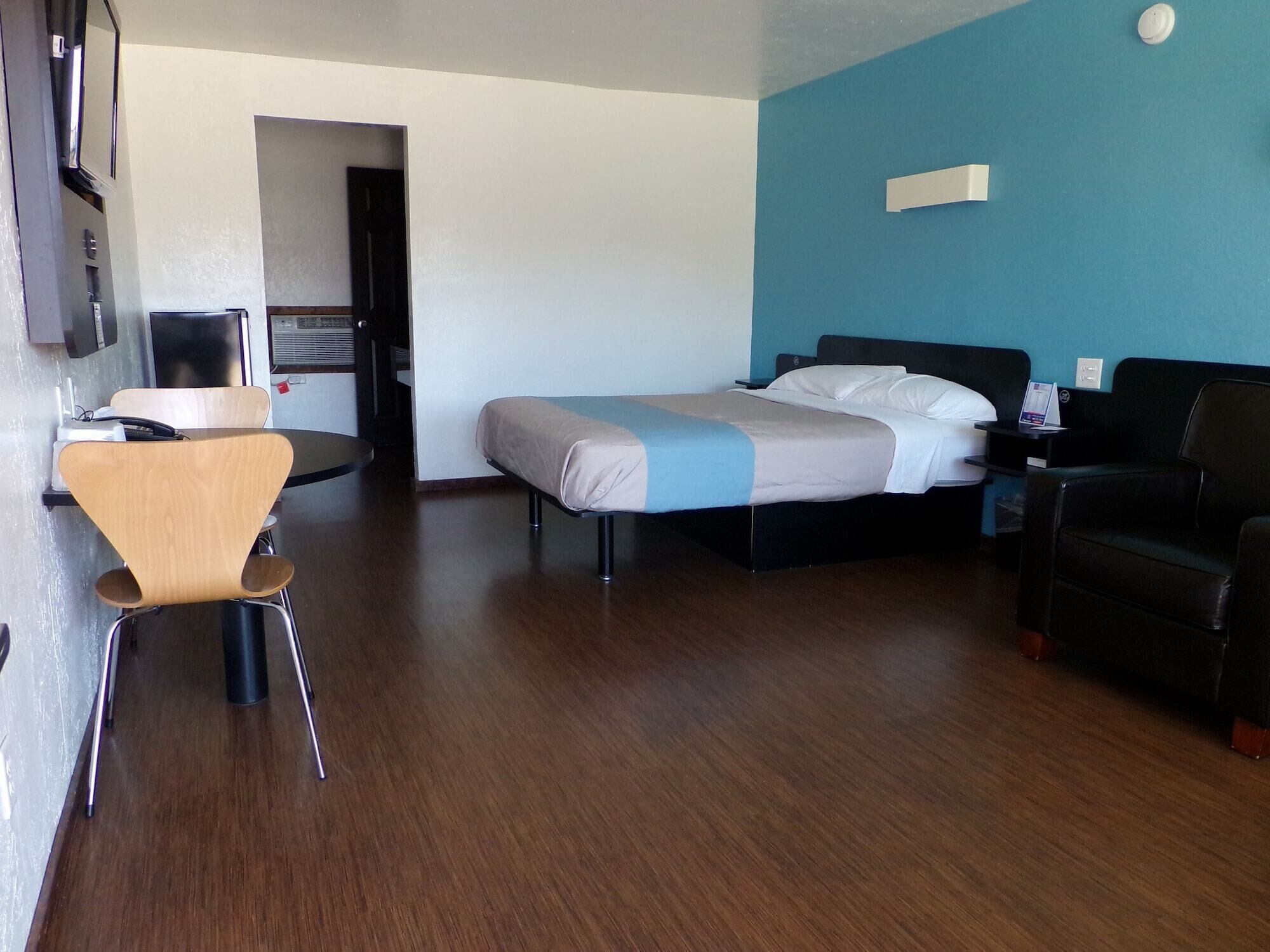 A hotel room with a bed, a desk, a chair, and a couch.