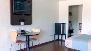 A hotel room with a bed, a desk with two chairs, a television mounted on the wall, and a door leading to another room. - Motel 6 University Missoula (Missoula)