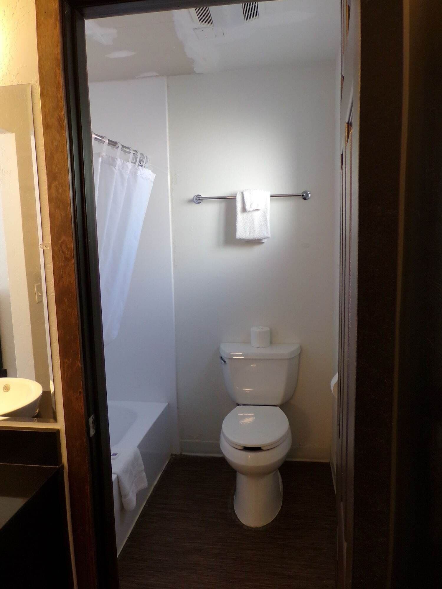 A small, compact bathroom with a toilet, a towel rack, and a shower curtain.