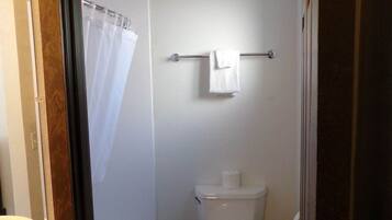 A small, compact bathroom with a toilet, a towel rack, and a shower curtain.