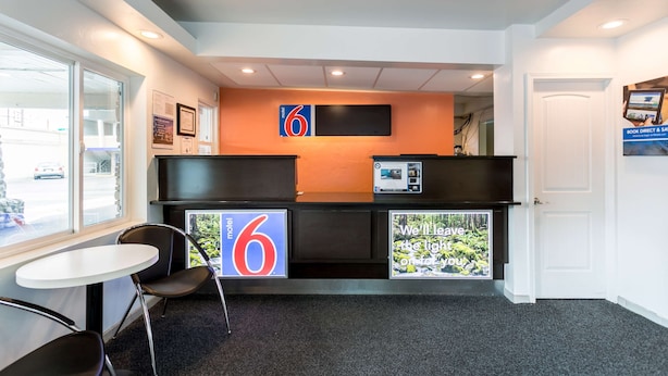 A reception area with a desk, chairs, a large number '6' sign, and a view through a glass door. - Motel 6 University Missoula (Missoula)