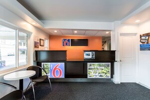 A reception area with a desk, chairs, a large number '6' sign, and a view through a glass door.