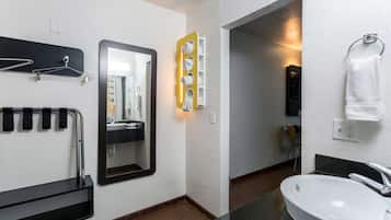 A modern bathroom with a black towel rack, a mirror, a white sink, and a towel hanging on a ring.