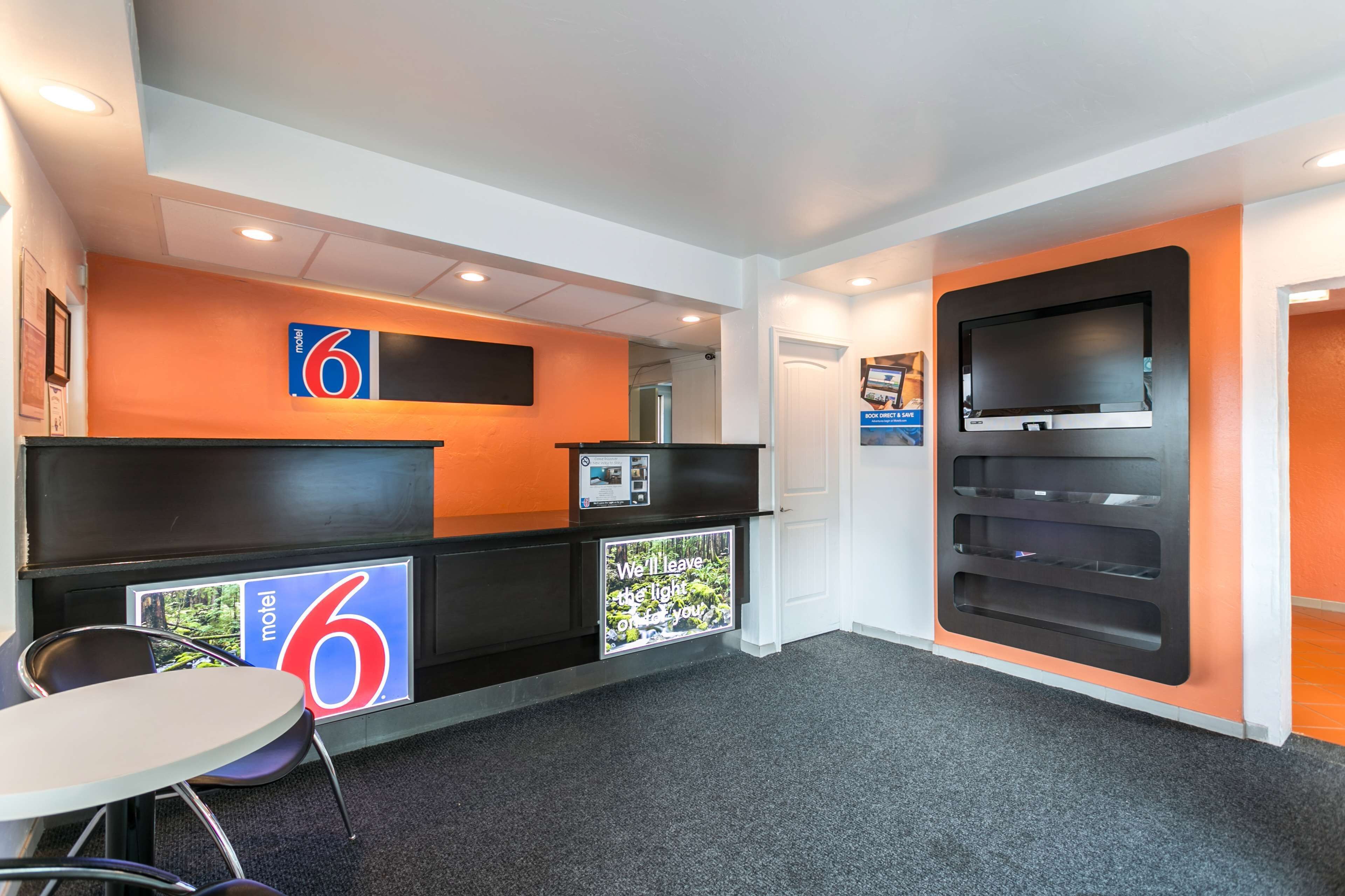 A reception area with a counter, a TV mounted on the wall, and a small table with chairs.