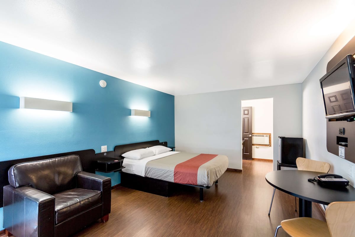 Ein Hotelzimmer mit Bett, Schreibtisch, Stuhl, Sofa und Fernseher.