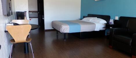 A hotel room with a bed, a desk, a chair, and a couch.