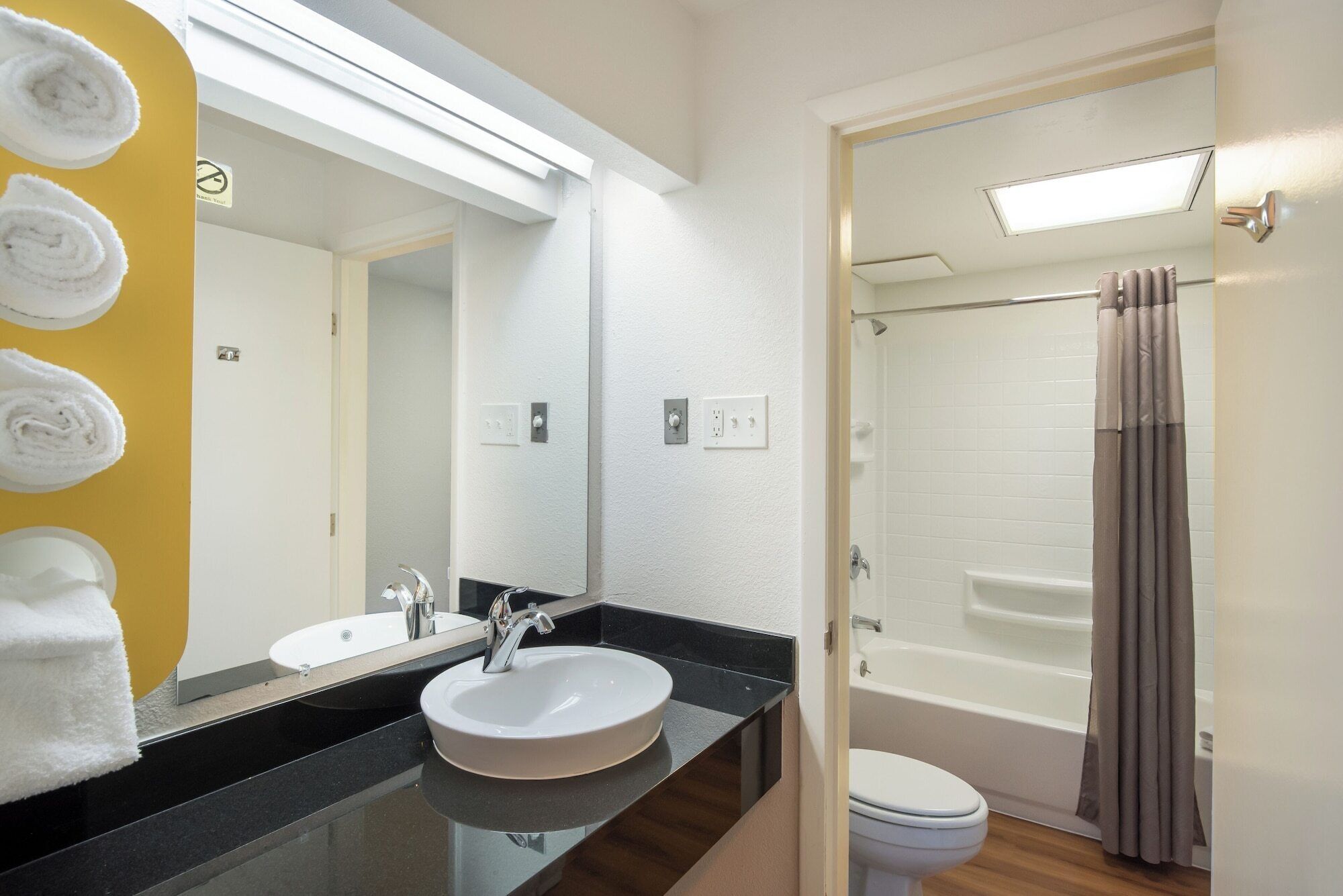 Un baño con lavamanos, espejo y ducha con cortina.